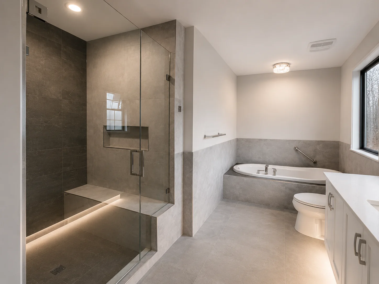 Gray stone walk-in shower beside a bathtub with clean glass and tile transitions