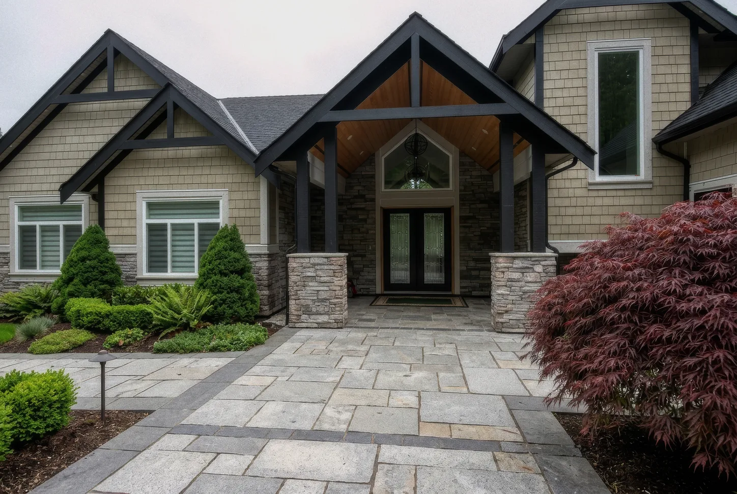 Modern craftsman home entry framed with stacked stone veneer