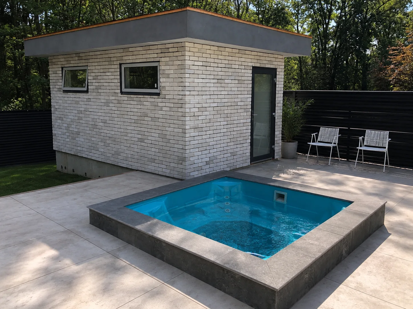 Outdoor porcelain patio tile around a pool and white brick pool house